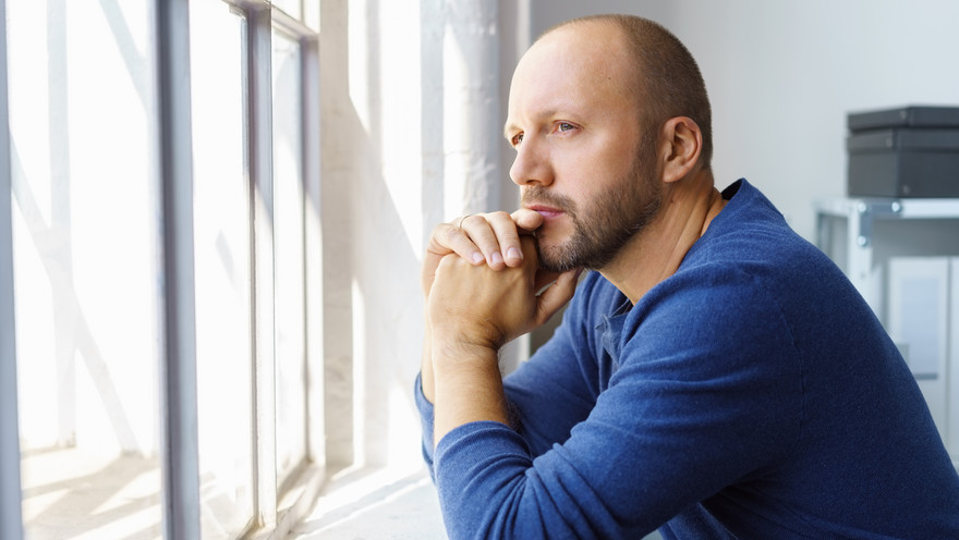 Mann schaut nachdenklich aus dem Fenster