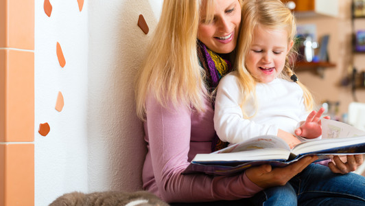 Eine Frau liest mit einem Kind ein Buch.