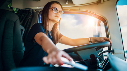 Frau mit Sonnenbrille sitzt hinter dem Steuer ihres Urlaubscampers