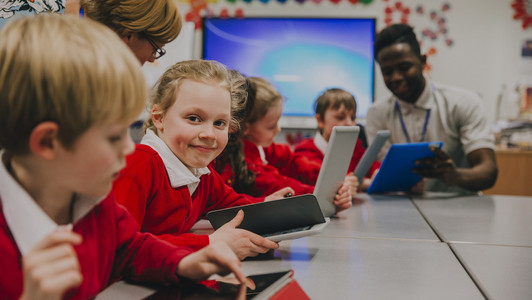 Kinder sitzen am Tisch und bedienen Tablets