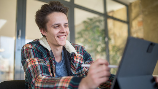 Student bedient ein Touch-Pad und lächelt dabei.