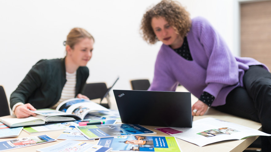 Die Redakteurinnen Hannah Fischer und Stephanie Fröba sitzen zusammen am Tisch und besprechen den neuen Blog am Laptop.