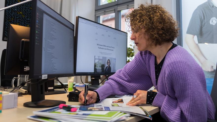 Redakteurin Stephanie Fröba macht sich am Arbeitsplatz Notizen und stellt Blogbeiträge online.