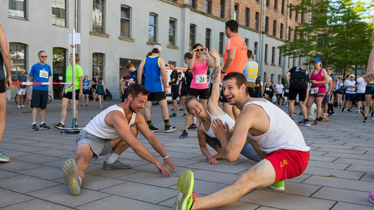 Eine Läuferin und zwei Läufer wärmen sich für den Uni-Lauf 2022 auf.