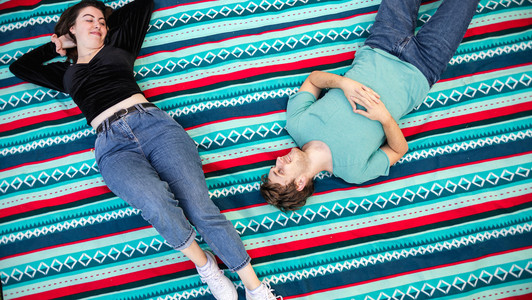 Die Studierenden Anna und Felix liegen auf einer Picknickdecke